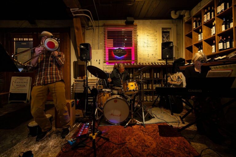 Live jazz band performing in an intimate venue with trombone, drums, and keyboard players.