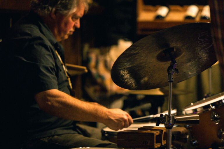 Drummer intensely playing in a dimly lit venue, highlighting live music ambiance.