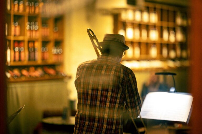 Musician with a trombone in a cozy, dimly lit bar with shelves of bottles in the background.