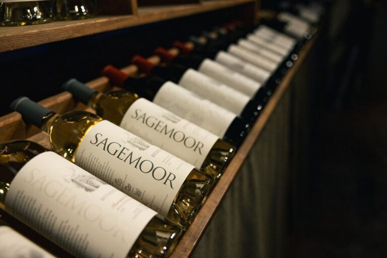 Row of Sagemoor wine bottles displayed on a wooden shelf in dim lighting.
